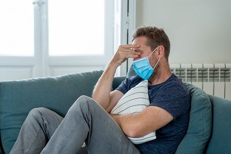 Hombre tumbado en el sofá con síntomas de Covid persistente o Long Covid
