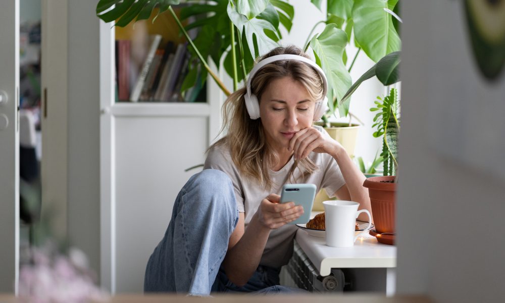 Una mujer joven escuchando audios con el móvil