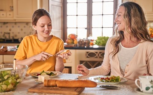 Dos mujeres comparten una comida saludable, un hábito relacionado con la prevención del cáncer de mama