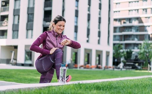 Mujer realizando estiramientos al aire libre antes de hacer ejercicio, uno de los hábitos que ayudan a reducir el riesgo de cáncer de mama