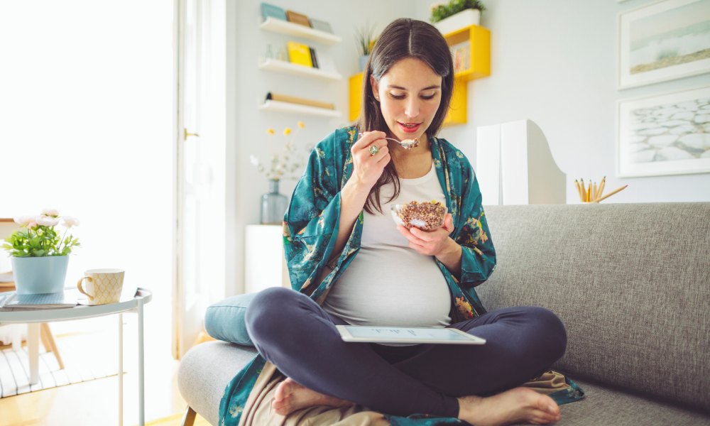 Una mujer embarazada comiendo un yogur