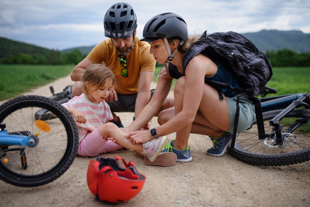Una padre y una madre atendiendo a su hija que ha sufrido una caída en bicicleta