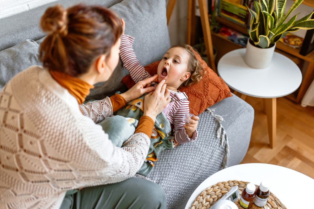 Una madre observa a su hija que tiene dolor de garganta
