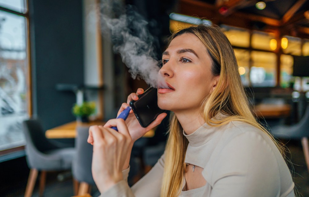 Mujer vapeando mientras habla por el móvil