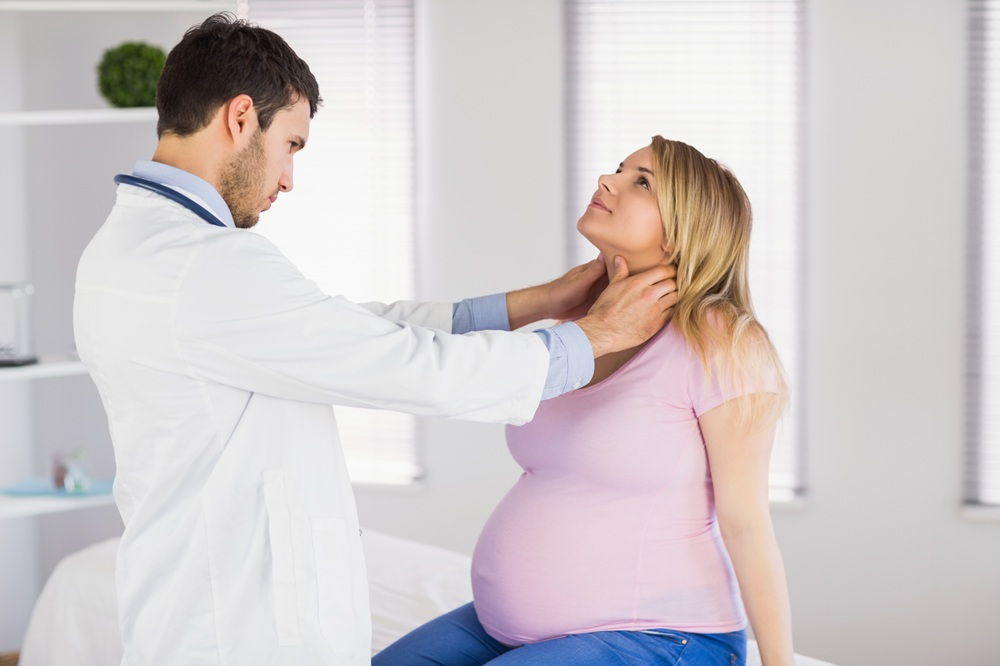 Doctor palpa el cuello de una mujer embarazada durante un examen del tiroides