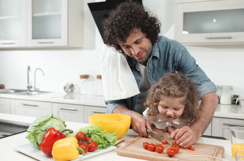 Padre e hija en la cocina preparando menús saludables