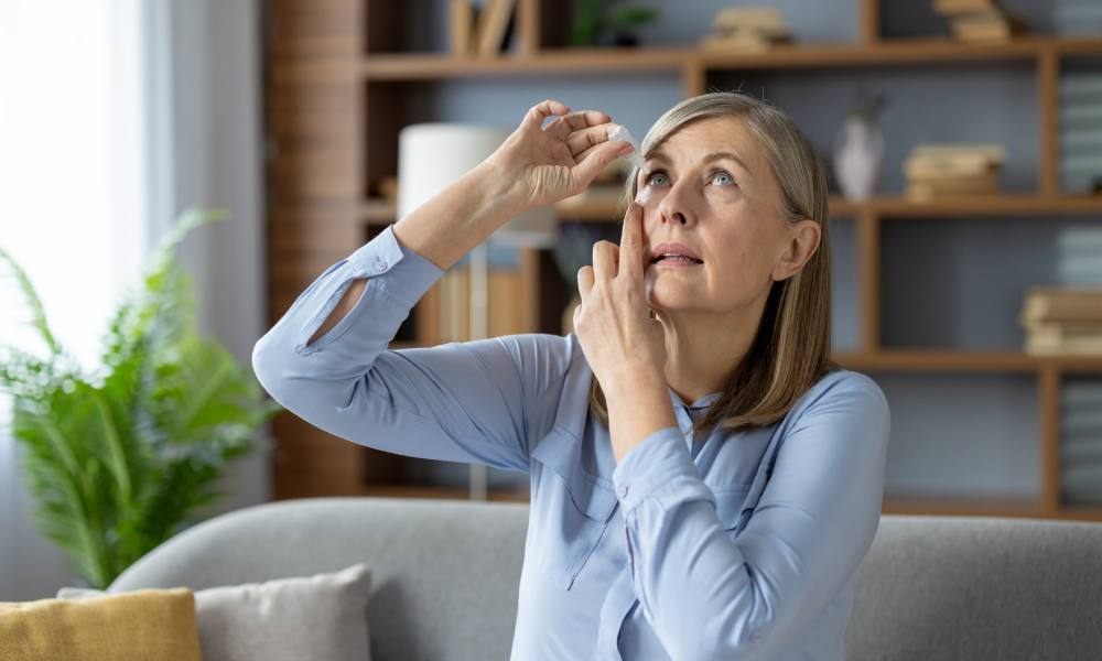 Una mujer se está echando gotas en el ojo derecho