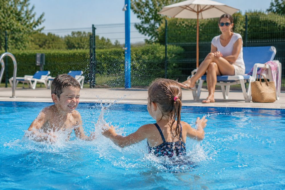 Una madre vigila a sus hijos, que están dentro de la piscina jugando